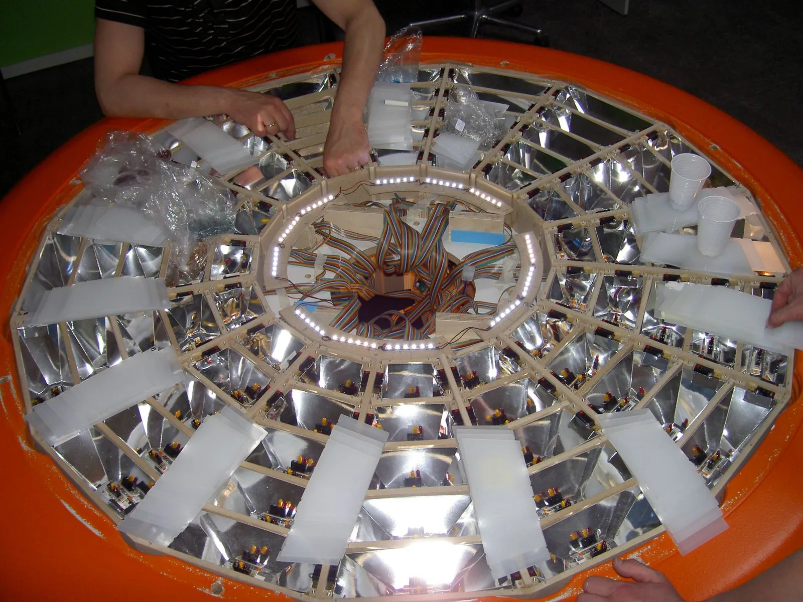 The table open during construction, showing the ring of reflector cells, the wiring loom and the white acrylic lids waiting to be fitted.